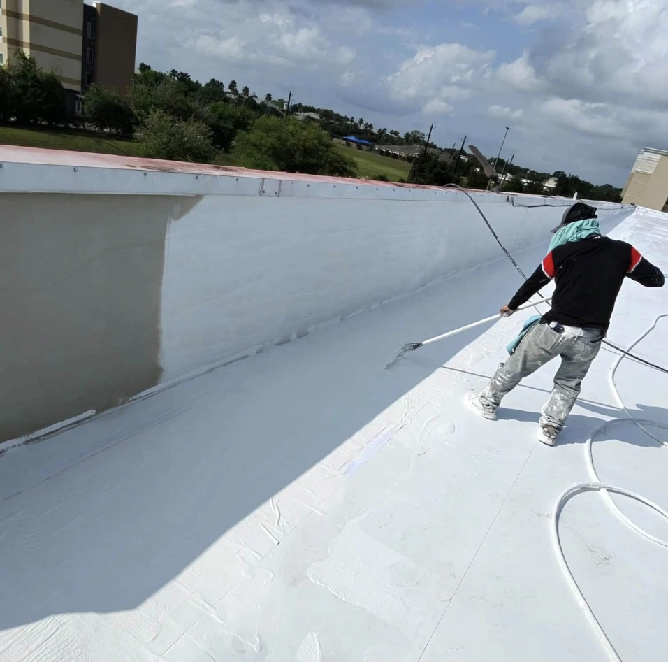 Bismarck, North Dakota commercial roofing contractor applying protective white coating to a flat roof membrane by Bismarck Exterior Pros.