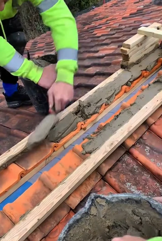Bismarck, North Dakota roofing contractor applying mortar to repair and secure terracotta roof tiles, professional roof repair services by Bismarck Exterior Pros.