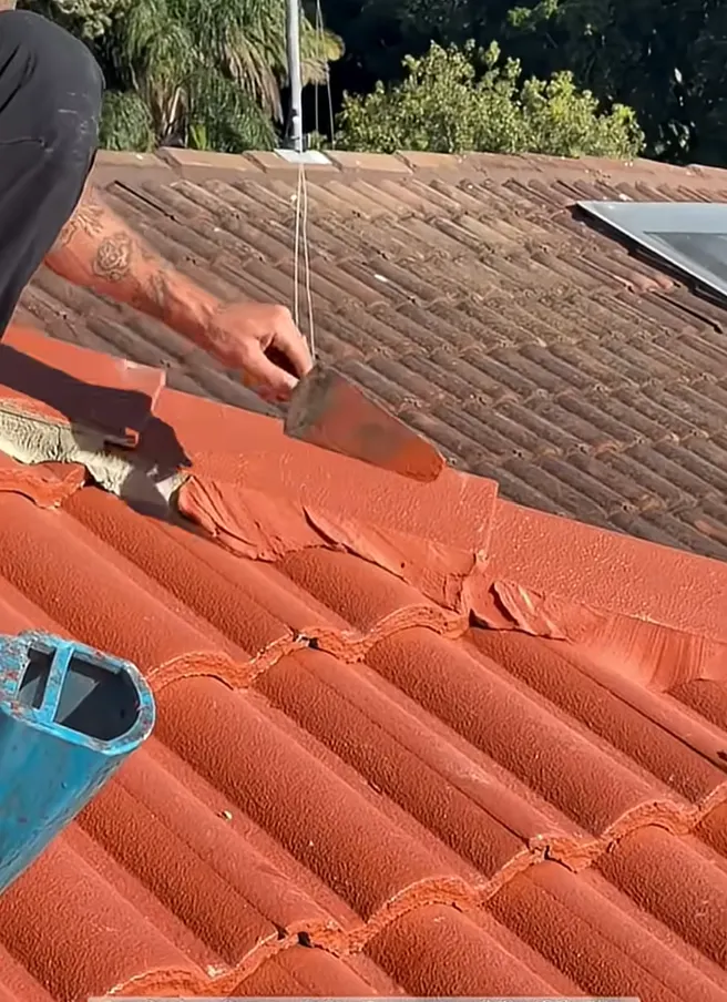 Bismarck roofing contractor using a trowel to apply mortar and repair terracotta roof tiles in Bismarck, North Dakota, by Bismarck Exterior Pros.