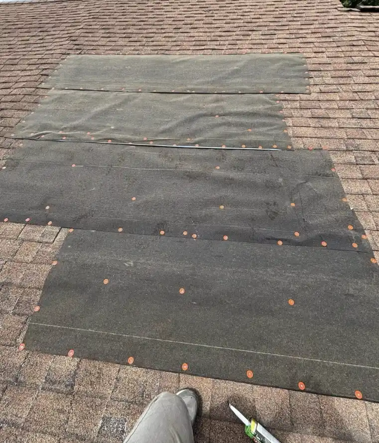 Storm damage roof repair in Bismarck, North Dakota, showing temporary tarp installation to protect damaged shingles by Bismarck Exterior Pros.