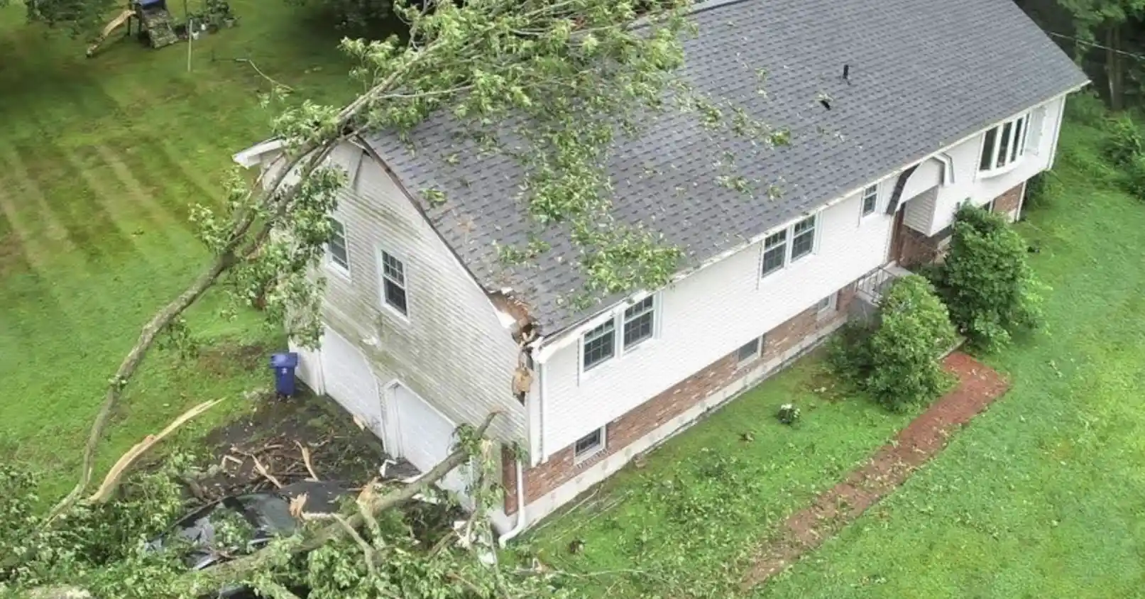 Storm damage in Bismarck, North Dakota, showing a fallen tree on a residential roof, professional emergency roof repair services by Bismarck Exterior Pros.